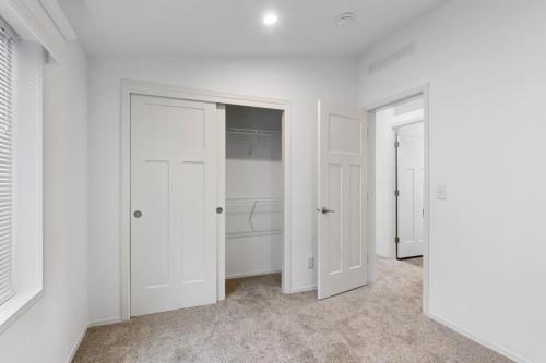 An empty room with white closet doors and carpet.