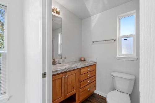 A white bathroom with wood floors and a window.