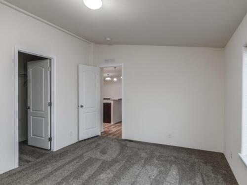 An empty room with gray carpet and a door.