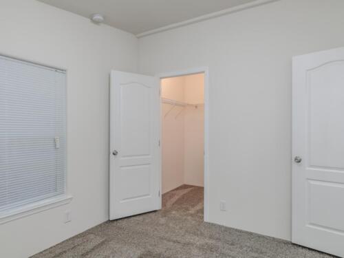 An empty room with two doors and a closet.