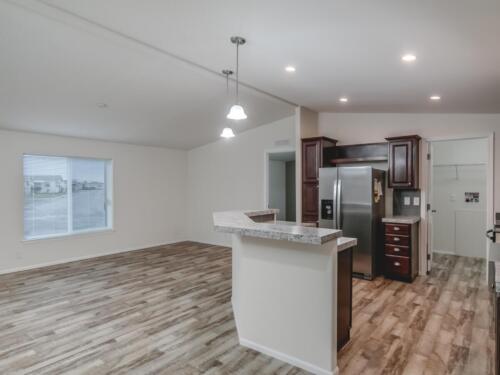 An empty kitchen with wood floors and stainless steel appliances.