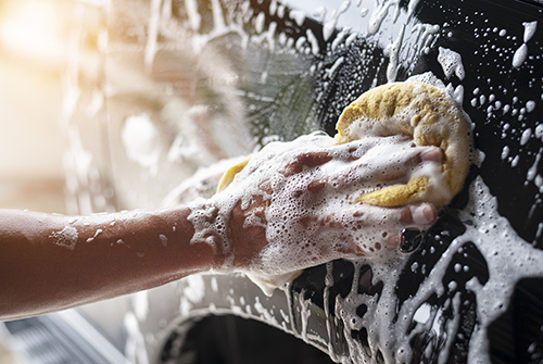 A person washing a car with a sponge.